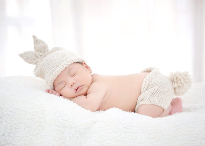 Lovely newborn Asian baby sleeping on furry cloth